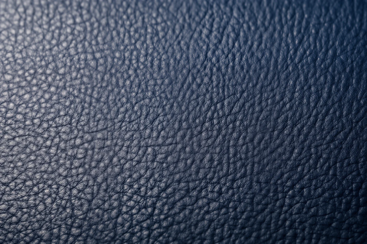 Macro photograph of slate blue full-grain leather showing natural pores and creases